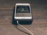 silver iphone with black case on brown surface