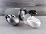 Wireless earphones and portable speaker displayed on a modern surface, showcasing sleek design and technology.