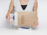 Person holding a new smartphone in packaging.