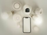 Flat lay of smart home devices with a smartphone controller on a white background.