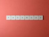 Focus on password security with white keyboard tiles spelling 'PASSWORD' on a coral background.