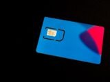 A blue sim card sits on a dark surface.