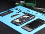 Disassembled smartphone with tools on a workbench, emphasizing repair and technology.