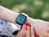 Woman interacting with a smartwatch outdoors displaying a fitness tracking app.