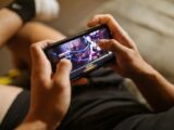 A person playing a mobile video game on a smartphone, focusing on gaming and technology lifestyle.