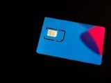 A blue SIM card on a dark background with vibrant red and purple accents.
