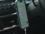 A smartphone with a map app displayed inside a car, showing modern navigation.