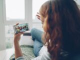 Woman relaxing indoors while video chatting with friends on smartphone.