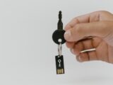 A close-up of a hand holding a key with an attached USB drive, highlighting security and technology.
