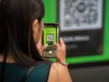 A woman uses her smartphone to scan a QR code in Mexico City, capturing modern technology in action.