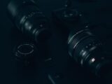 A detailed view of various camera lenses and accessories arranged on a dark surface.