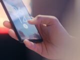 Close-up of a hand holding a smartphone locked with a fingerprint sensor.