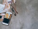 Mobile phone and eyeglasses on a concrete surface with photographs and a memory card.
