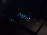 Close-up of a smartphone in the dark displaying digital clock and notifications.