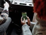 Two people using a navigation app on a smartphone during a road trip
