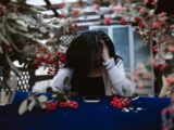 Woman in despair at table with red berries and smartphone, hands on head.
