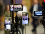 Multiple mobile phones capturing a live event at a prominent landmark in Oslo, Norway.