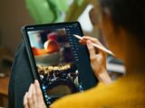 A woman uses a stylus to edit photos on a tablet, showcasing freelance creativity.