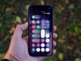 Hand holding a smartphone with colorful app icons.