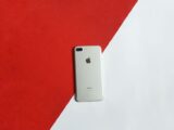 A silver smartphone placed on a contrasting red and white background captured from above.