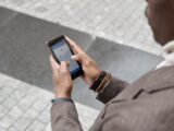 A stylish professional adult using a smartphone with a navigation app on an urban street.