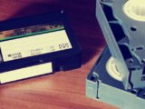 Close-up of vintage VHS tapes on a wooden table, highlighting old technology and nostalgia.